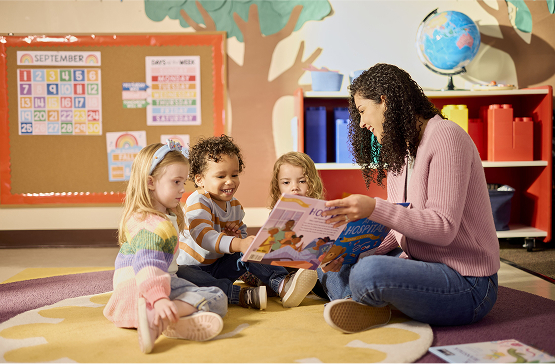 A Gen Z school teacher is sitting on the floor with her children reading them a book